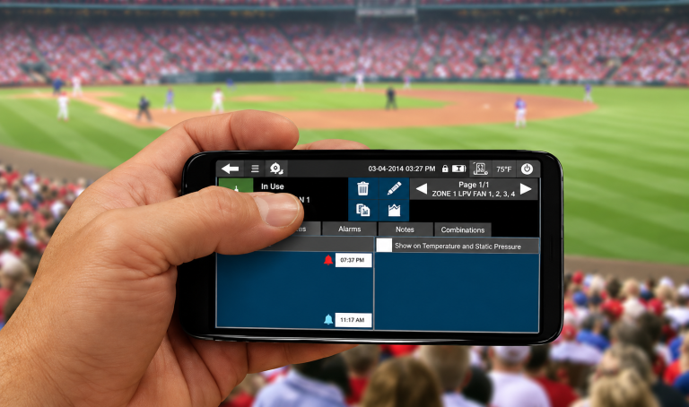Smartphone displaying a farm monitoring dashboard while being used remotely at a baseball stadium.