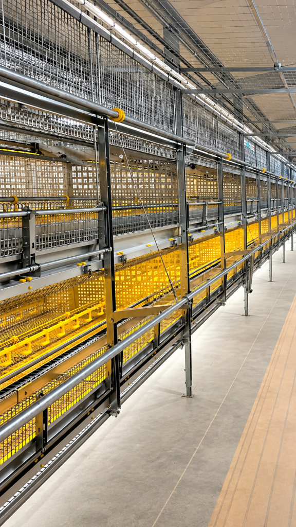 LANDMECO High Raise Aviary System featuring multi-tier galvanized steel pullet housing, mesh partitions, access rails and yellow flooring components.