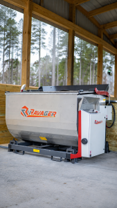 Ravager poultry mortality dehydrator with stainless steel processing drum and control cabinet inside a covered agricultural structure.